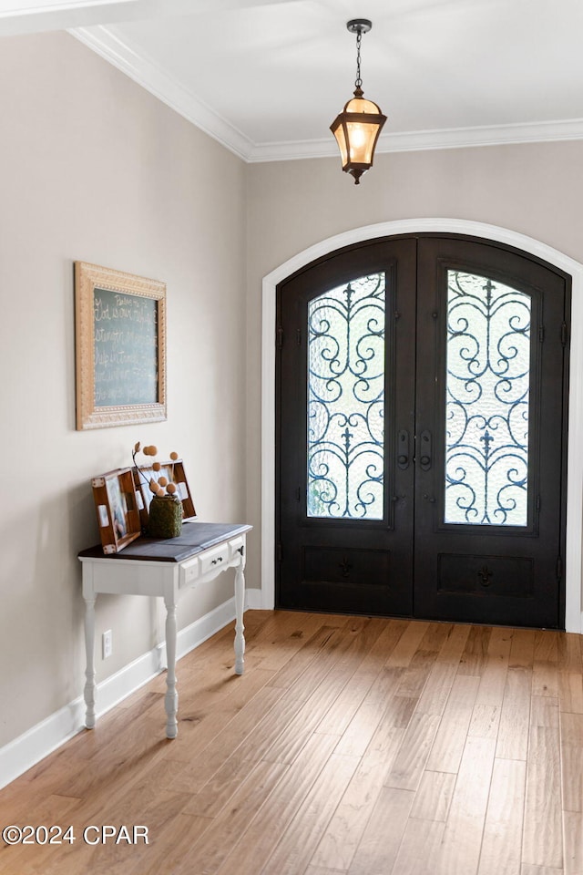 foyer entrance with light hardwood / wood-style flooring, crown molding, and french doors