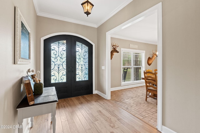 entryway with french doors, crown molding, and light hardwood / wood-style floors