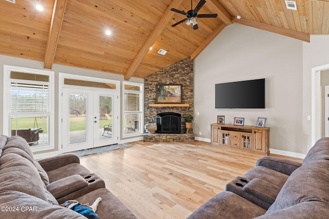 living room with beamed ceiling, a large fireplace, and light hardwood / wood-style floors