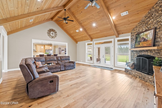 living room featuring high vaulted ceiling, a stone fireplace, ceiling fan, light hardwood / wood-style floors, and beamed ceiling