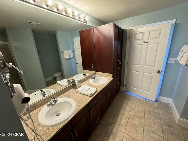 bathroom featuring vanity, tile patterned flooring, toilet, and a textured ceiling