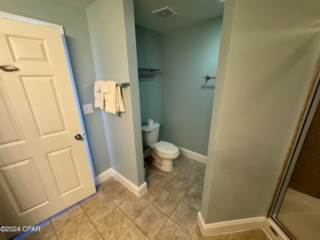 bathroom featuring tile patterned flooring, toilet, and an enclosed shower