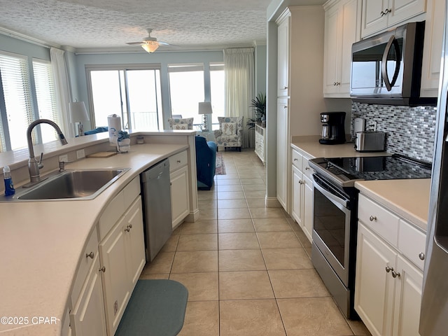 kitchen featuring light tile patterned flooring, a wealth of natural light, sink, white cabinets, and stainless steel appliances