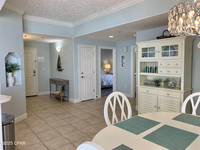 tiled dining space featuring an inviting chandelier, ornamental molding, and a textured ceiling