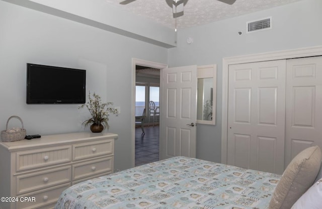 tiled bedroom featuring ceiling fan, a textured ceiling, and a closet