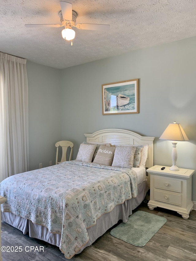 bedroom with ceiling fan, dark hardwood / wood-style flooring, and a textured ceiling