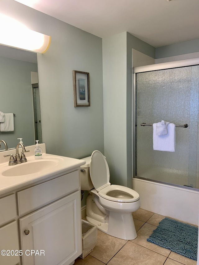 full bathroom featuring tile patterned flooring, bath / shower combo with glass door, vanity, and toilet