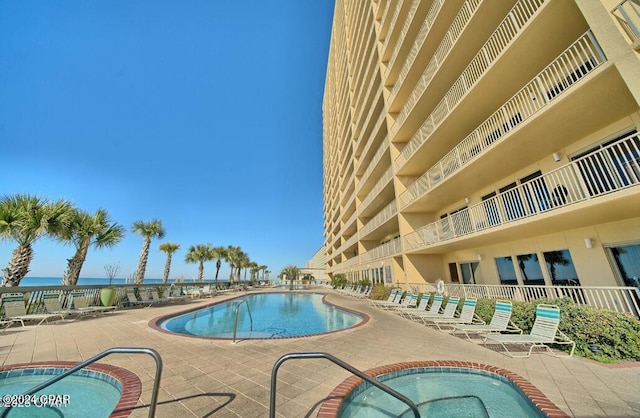 view of pool featuring a patio, a water view, and a community hot tub