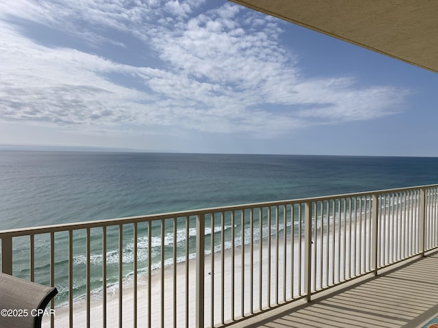 balcony with a water view and a view of the beach