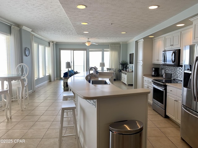 kitchen featuring white cabinetry, sink, a kitchen bar, stainless steel appliances, and a center island with sink