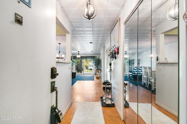 corridor featuring a notable chandelier and light wood-type flooring