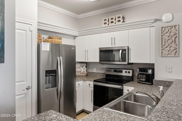 kitchen featuring dark stone counters, white cabinets, crown molding, stainless steel appliances, and sink