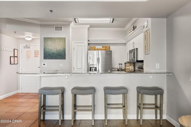 kitchen featuring tile flooring, stainless steel appliances, white cabinetry, and light stone counters