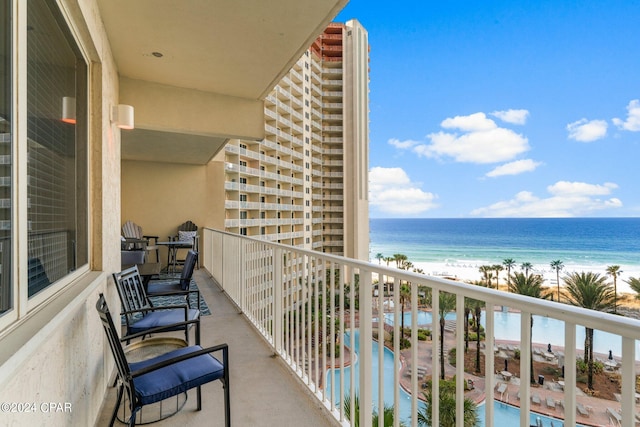 balcony with a water view and a view of the beach