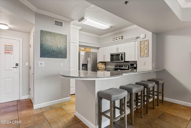 kitchen with kitchen peninsula, white cabinetry, stone counters, appliances with stainless steel finishes, and light tile floors