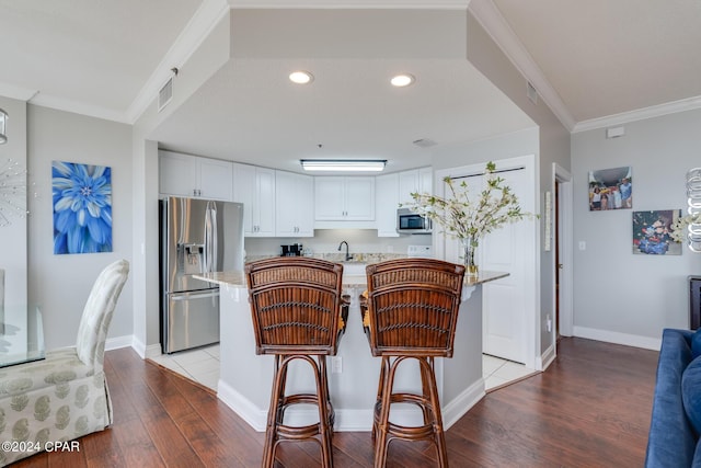 kitchen featuring ornamental molding, stainless steel appliances, sink, white cabinets, and light hardwood / wood-style floors