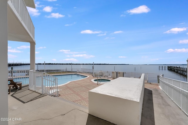 view of swimming pool with a patio area, a community hot tub, and a water view