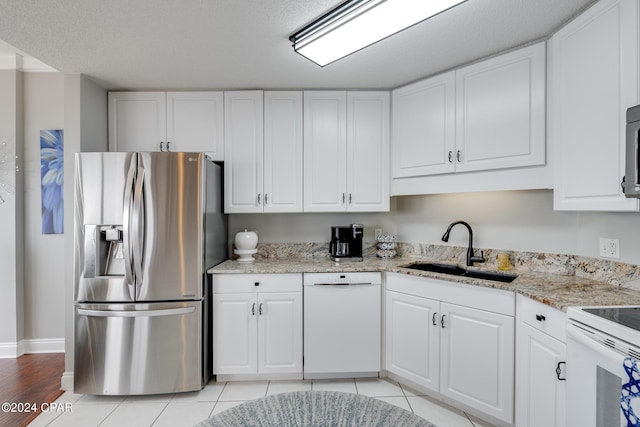 kitchen featuring white appliances, white cabinets, sink, light stone countertops, and light tile patterned flooring