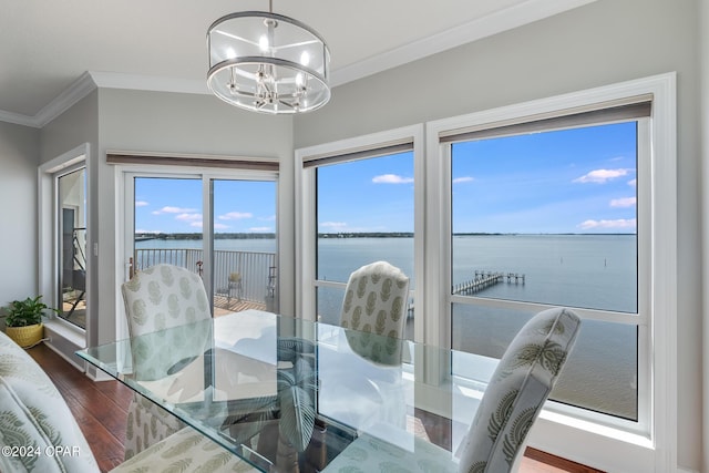 dining space with crown molding, dark hardwood / wood-style flooring, a water view, and a chandelier