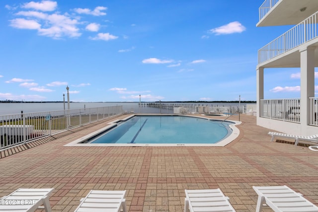 view of pool with a water view and a patio