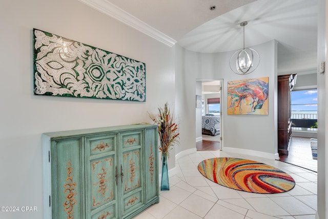 corridor featuring a notable chandelier, light tile patterned floors, and crown molding