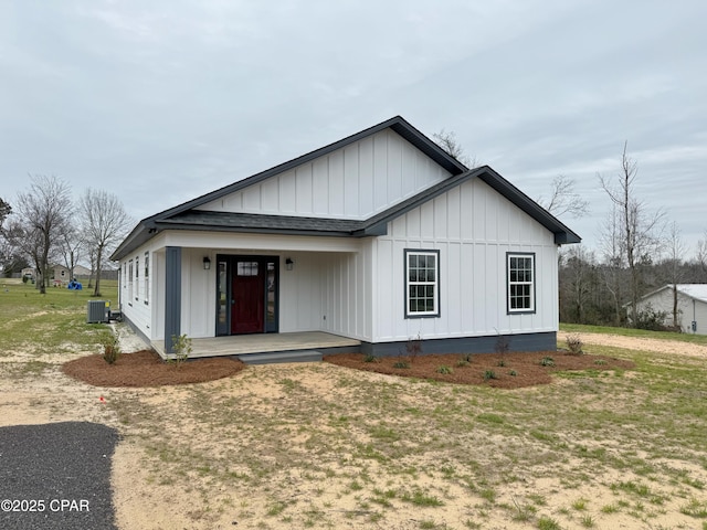 view of front of property featuring central AC unit, a front lawn, board and batten siding, and roof with shingles