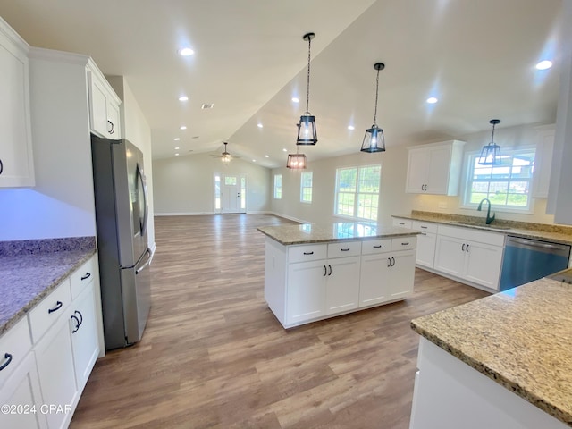 kitchen with a center island, hanging light fixtures, appliances with stainless steel finishes, open floor plan, and white cabinets