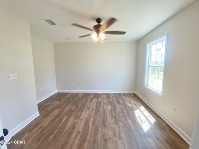 empty room featuring a ceiling fan, dark wood-style flooring, visible vents, and baseboards