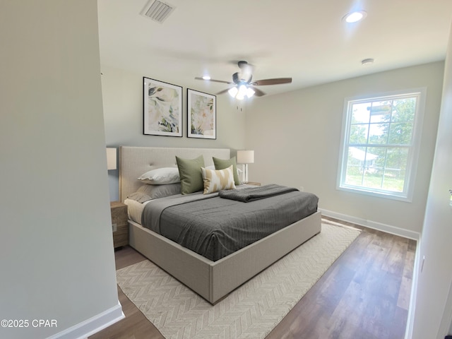 bedroom with wood finished floors, visible vents, and baseboards