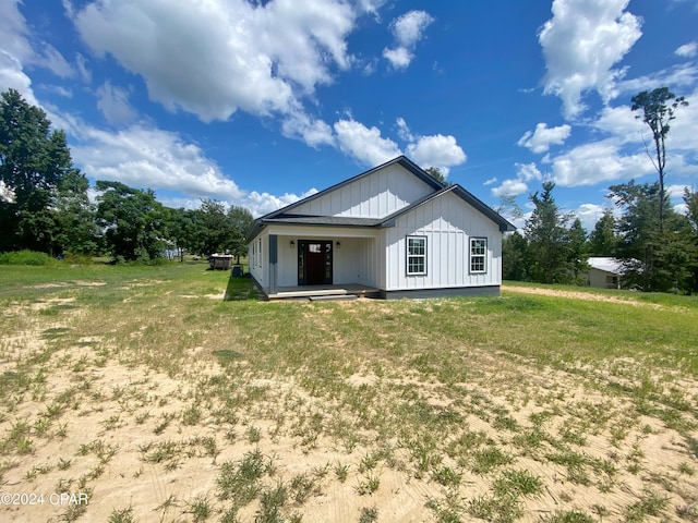 back of property featuring a yard and covered porch