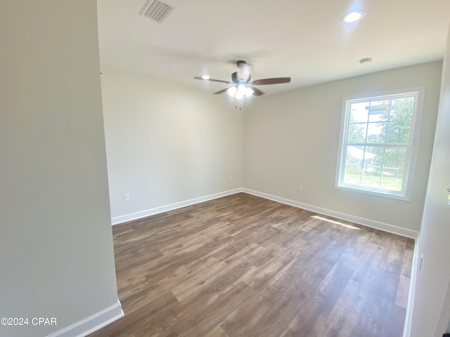 unfurnished room featuring a ceiling fan, visible vents, baseboards, and wood finished floors