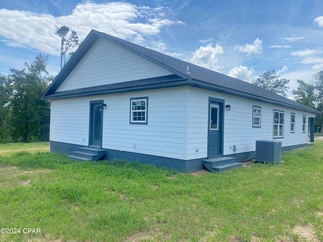 rear view of property with entry steps, a yard, roof with shingles, and central air condition unit