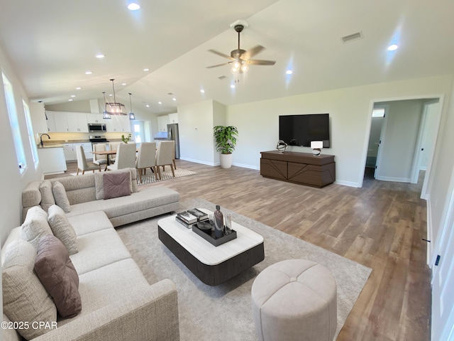 living area with lofted ceiling, recessed lighting, visible vents, and light wood-style floors