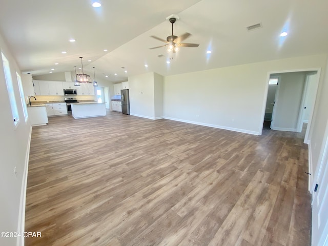 unfurnished living room featuring lofted ceiling, light wood-style flooring, visible vents, and a sink