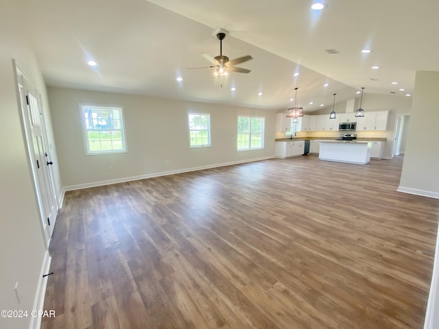 unfurnished living room featuring lofted ceiling, baseboards, recessed lighting, and wood finished floors