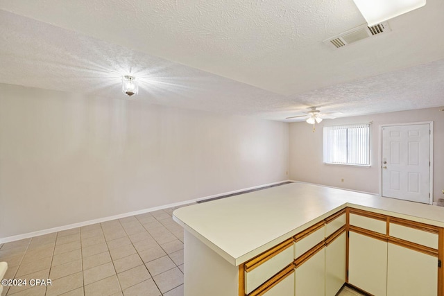 kitchen featuring ceiling fan, a textured ceiling, light tile patterned flooring, and kitchen peninsula