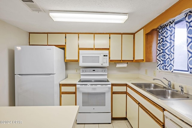 kitchen featuring white appliances, sink, a textured ceiling, white cabinets, and light tile patterned floors