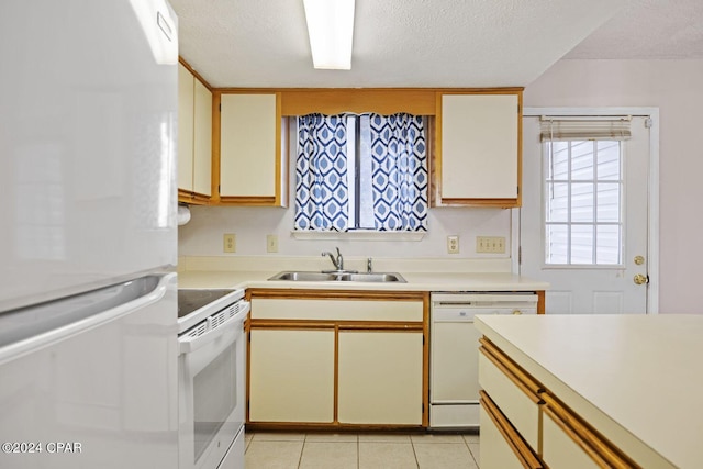 kitchen featuring a textured ceiling, sink, light tile patterned floors, and white appliances