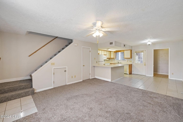 unfurnished living room featuring ceiling fan, a textured ceiling, sink, and light colored carpet