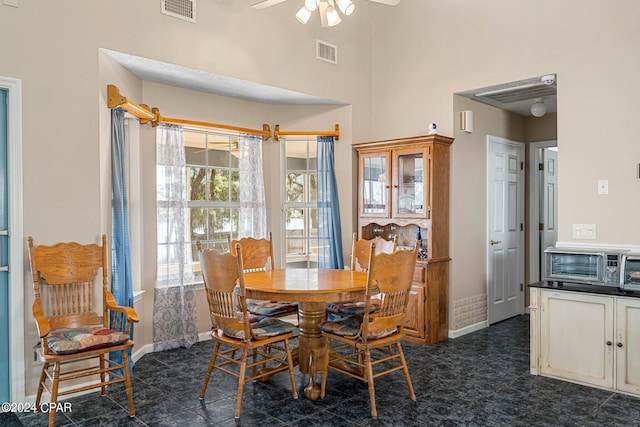 tiled dining area featuring a high ceiling and ceiling fan