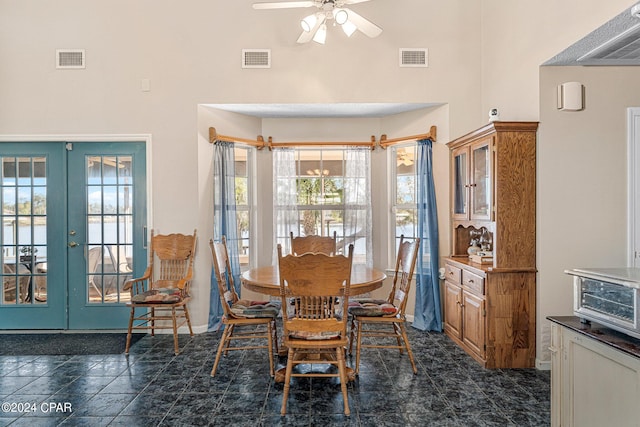 tiled dining area with french doors, ceiling fan, a wealth of natural light, and a towering ceiling