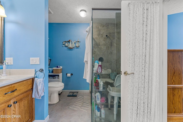 bathroom featuring tile floors, tiled shower, a textured ceiling, vanity with extensive cabinet space, and toilet