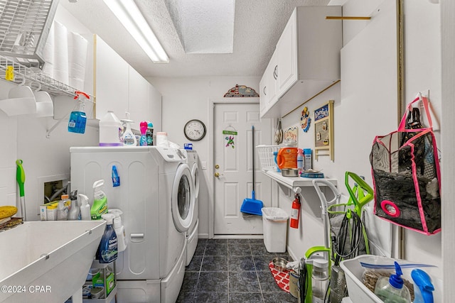 laundry room with a textured ceiling, separate washer and dryer, cabinets, and dark tile flooring