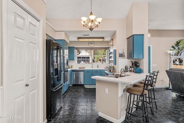 kitchen with a chandelier, stainless steel appliances, a kitchen bar, blue cabinets, and dark tile flooring