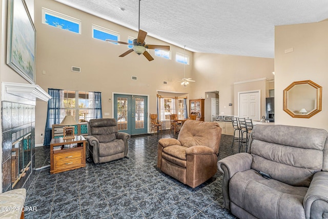 living room with a tile fireplace, high vaulted ceiling, ceiling fan, a textured ceiling, and dark tile floors