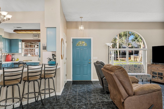 foyer entrance featuring dark tile flooring, a textured ceiling, and a chandelier