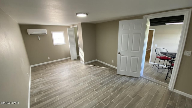 spare room with light hardwood / wood-style floors and a wall unit AC