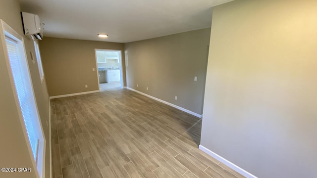 empty room with an AC wall unit and light wood-type flooring