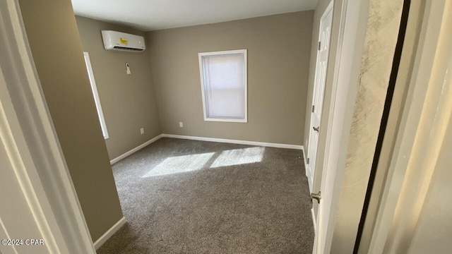 spare room featuring an AC wall unit and dark colored carpet