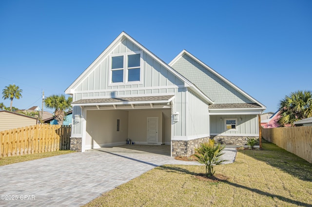 view of front facade featuring decorative driveway, fence, board and batten siding, and stone siding